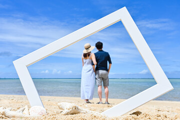 沖縄のビーチでフォトフレームの中にいるかのように撮影したカップルのイメージ写真