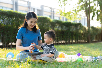 Asian mother and son doing activities together in the grass