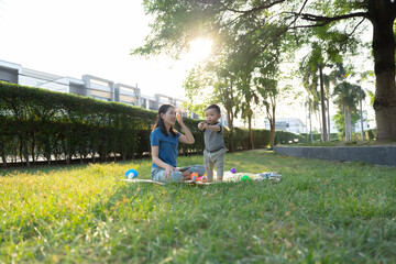 Asian mother and son doing activities together in the grass