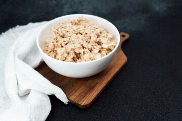 Oatmeal served in a white bowl on a wooden cutting board