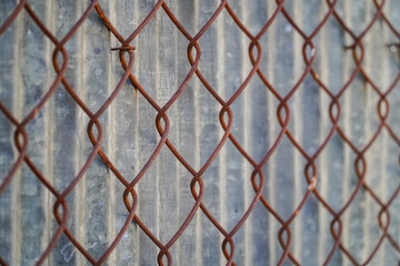 Naklejka premium A close-up perspective of a rusted wire fence against a textured background presents industrial textures and geometric patterns. Rust colored metal links creates visual interest.