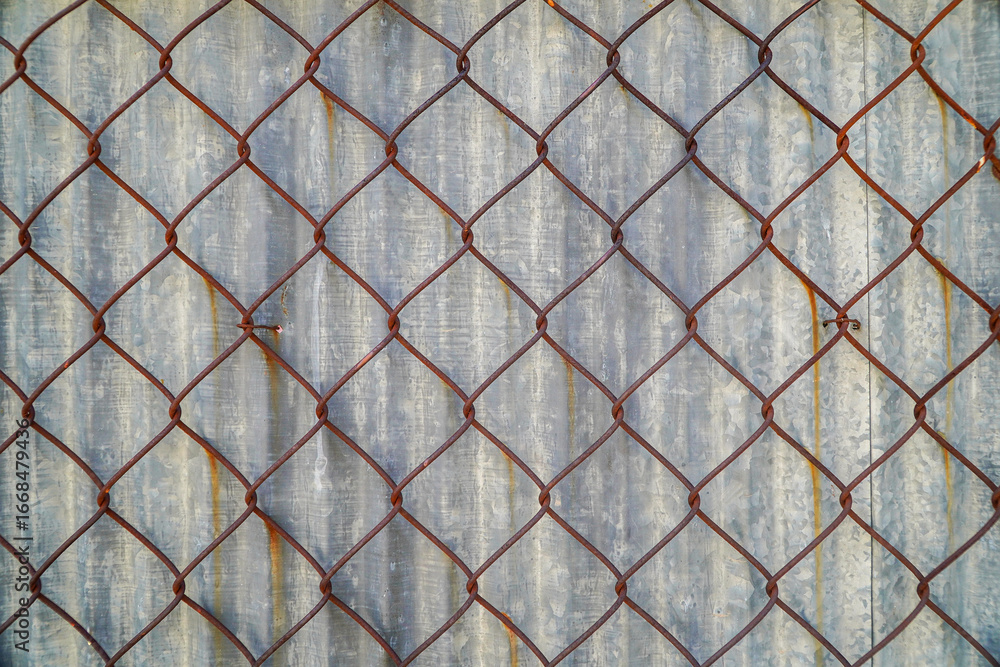 Poster an aged chain-link fence with rust against a corrugated metal backdrop. the geometric pattern and we