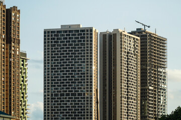 Fototapeta premium Skyscrapers rise against the bright sky. Modern buildings are a testament to urban development, showcasing architectural designs that reach for the heavens and represent a future-focused lifestyle.