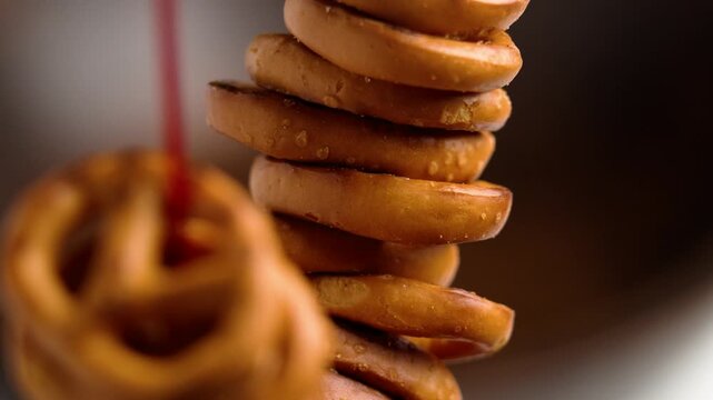 Salted pretzels crackers in bunch hanging on red string on brown background. Macro