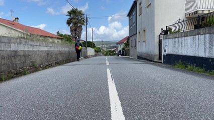 Hiker standing on a quiet, empty road with portugues street, surrounded by houses and trees