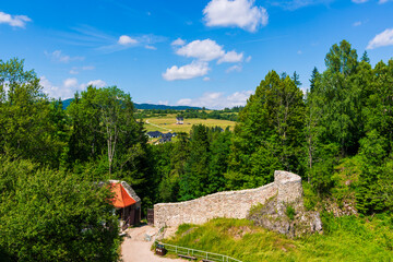 Remains of the stone defensive wall of Czorsztyn Castle overlook green meadows and distant hills....