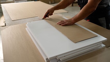 Furniture factory worker wrapping white doors in cardboard
