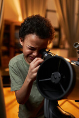 Vertical medium close-up portrait of modern young African American kid enjoying watching stars and...