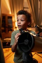 Vertical portrait of curious gen Alpha African American kid enjoying watching stars and planets in...