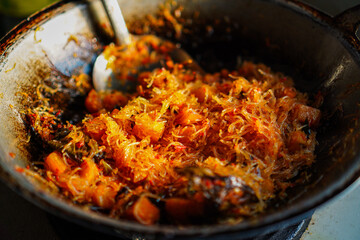 Aromatic stir-fry, expertly prepared. The dish features glistening noodles and vibrant vegetables in a rich, savory sauce. The cooking process is captured showing a flavorful meal.