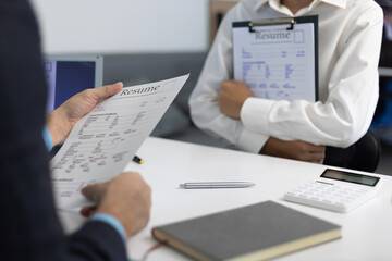 Employer reviewing resume during job interview in office. Human resources manager reading...