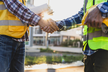 Construction workers shaking hands at construction site, agreement and partnership in a project.