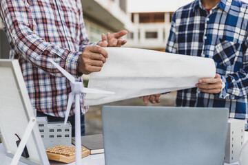 Construction workers are discussing blueprints on a job site, teamwork and project planning in the...