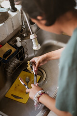 Teen female person washing kitchen utensils in the sink after finish cooking. motion blur.
