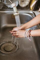 Young female person washing her hands in kitchen sink under running water from a tap after finish washing the dishes. motion blur.