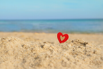 Fototapeta premium decorative heart on sand beach close up, tropical seascape background. symbol of Valentine's day. love of travel, romantic vacation, relax, spa concept. World Maritime Day. copy space