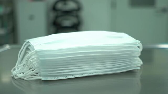 Stack of white sterile face masks on a reflective surface