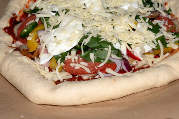 Close up of home made pizza with fresh dough and toppings ready to be cooked