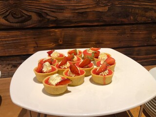 Strawberry tartlets on a white plate, delicious dessert