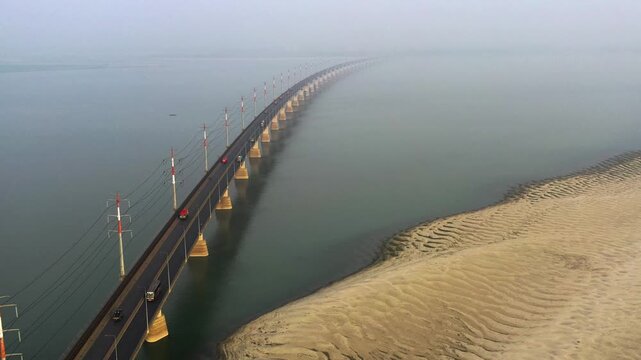 Sirajganj, Bangladesh - 23 August 2025: Aerial view of Bangabandhu bridge stretching across the water, flanked by rippled sandbanks under a misty sky.