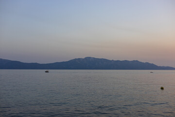 Quiet sunset over the sea with a boat and mountains on the horizon. Podaca village, Makarska...