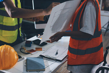 Closeup of team of industrial engineers meeting analyze machinery blueprints consult project on...