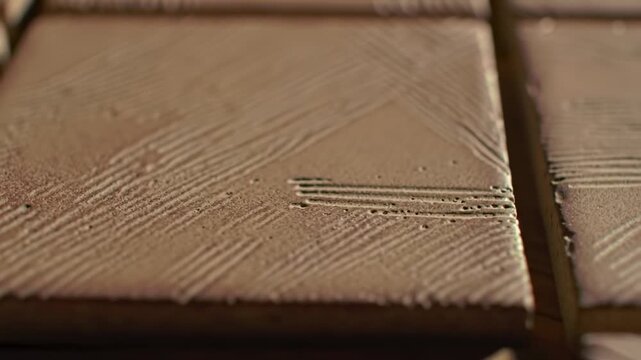 Close-up of textured, square tiles with a subtle linear pattern