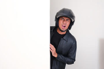 Motorcycle rider wearing helmet peeking from behind wall showing disappointed expression