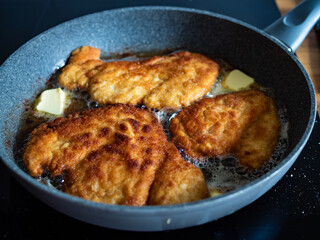 Frying crispy breaded chicken cutlets in frying pan, close-up