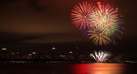 Spectacular fireworks illuminate the night sky above a vibrant cityscape reflecting in the tranquil water during a festive celebration