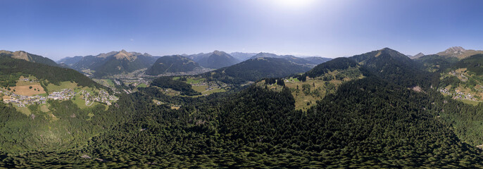 Super wide angle aerial panorama of mountain slope with green meadows and pine tree divide with cloud obscuring half of the scenery. Picturesque colorful high altitude weather condition concept.