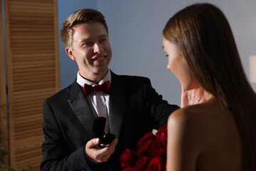 Smiling man with engagement ring making marriage proposal to his girlfriend at home