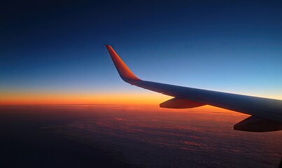 Airplane wing against a vibrant sunset over a cloud layer