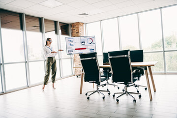 Young Businesswoman Presenting Analytics in a Modern Office with a Bright Atmosphere and...