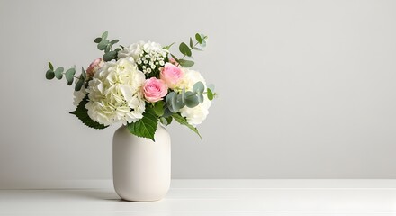 Naklejka premium Bouquet of white and pink flowers in a white vase on a white table against a light gray background wall