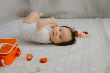 Cute Baby Rolling on Side with Wooden Doctor Toys Sweet baby wearing a striped onesie rolling onto...