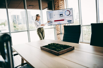 Charming businesswoman presenting a professional report on a digital display in a modern...