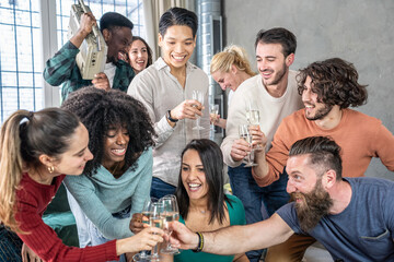 Group of young multiethnic friends celebrating together with champagne and laughter in a lively indoor party. Millennials and gen z enjoying music, fun and toasts. Happiness and friendship concept.