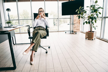 Young professional businesswoman sitting in a modern office space with stylish decor and natural...