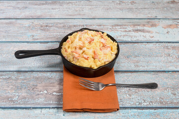 A delicious helping of lobster mac and mini iron cast skillet on a rustic table top. 
