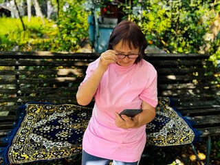 an elderly woman talking on a mobile phone outdoors