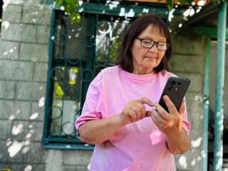 an elderly woman talking on a mobile phone outdoors