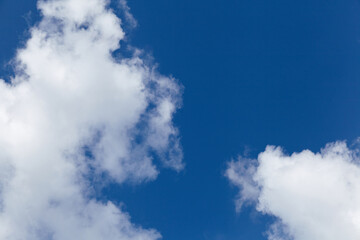 Obraz premium Bright blue sky filled with fluffy white clouds creating a serene atmosphere, ideal for backgrounds, designs, or nature-themed projects with ample copy space for text