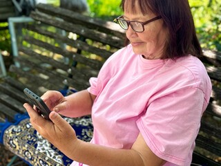 an elderly woman talking on a mobile phone outdoors