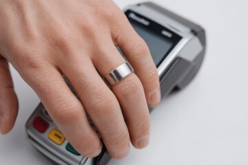 Close-up of hand wearing minimalist metal smart ring making contactless payment on terminal