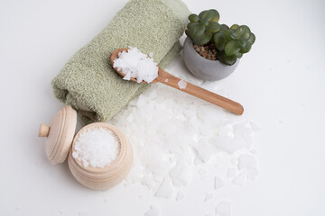 Close-up of magnesium salt flakes. Spa body care and magnesium therapy. White salt, cotton towels,...