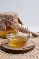 Jar of honey with wooden honey dipper on white kitchen background. Tasty honey bunker.