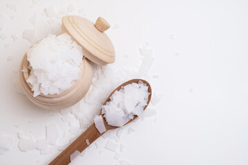Close-up of magnesium salt flakes. Spa body care and magnesium therapy. White salt, cotton towels,...