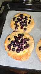 Homemade baked buns with cottage cheese and fresh blueberries on parchment paper. Concept of rustic baking, comfort food and sweet homemade dessert