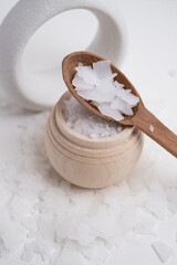 Close-up of magnesium salt flakes. Spa body care and magnesium therapy. White salt, cotton towels, eco-friendly products for home relaxation spa.